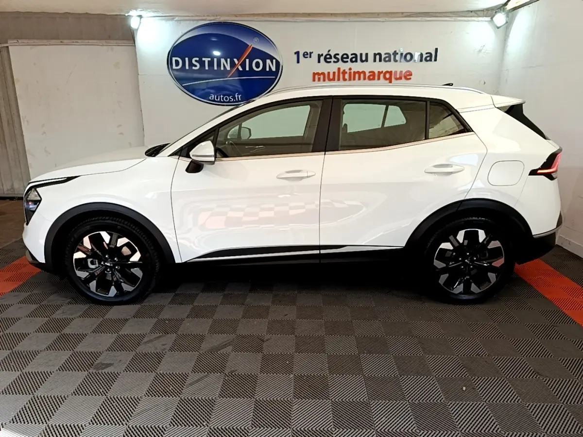 Vue latérale droite d'un KIA SPORTAGE blanc 2022 hybride rechargeable avec jantes noires et toit blanc.