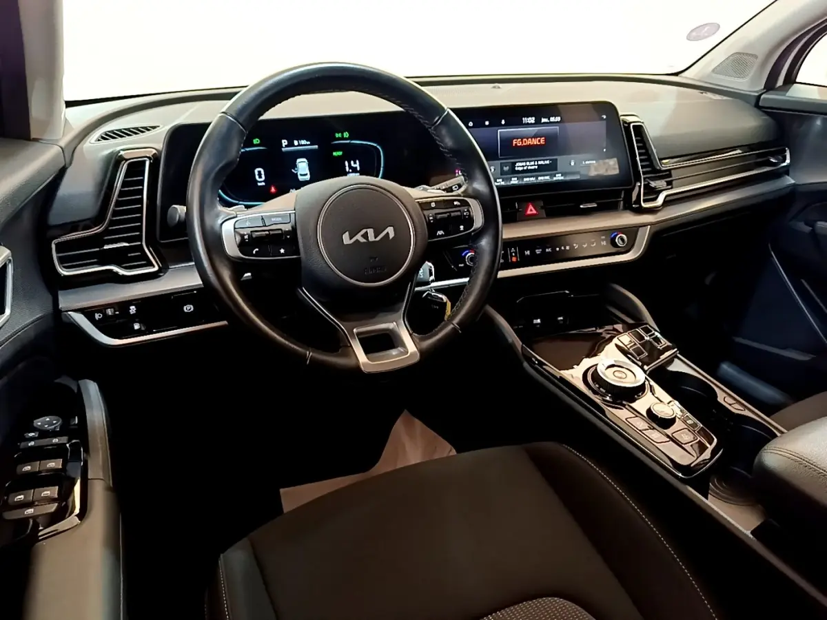 Vue intérieure du tableau de bord et volant noir du Kia Sportage hybride rechargeable 2022, avec écran tactile large.