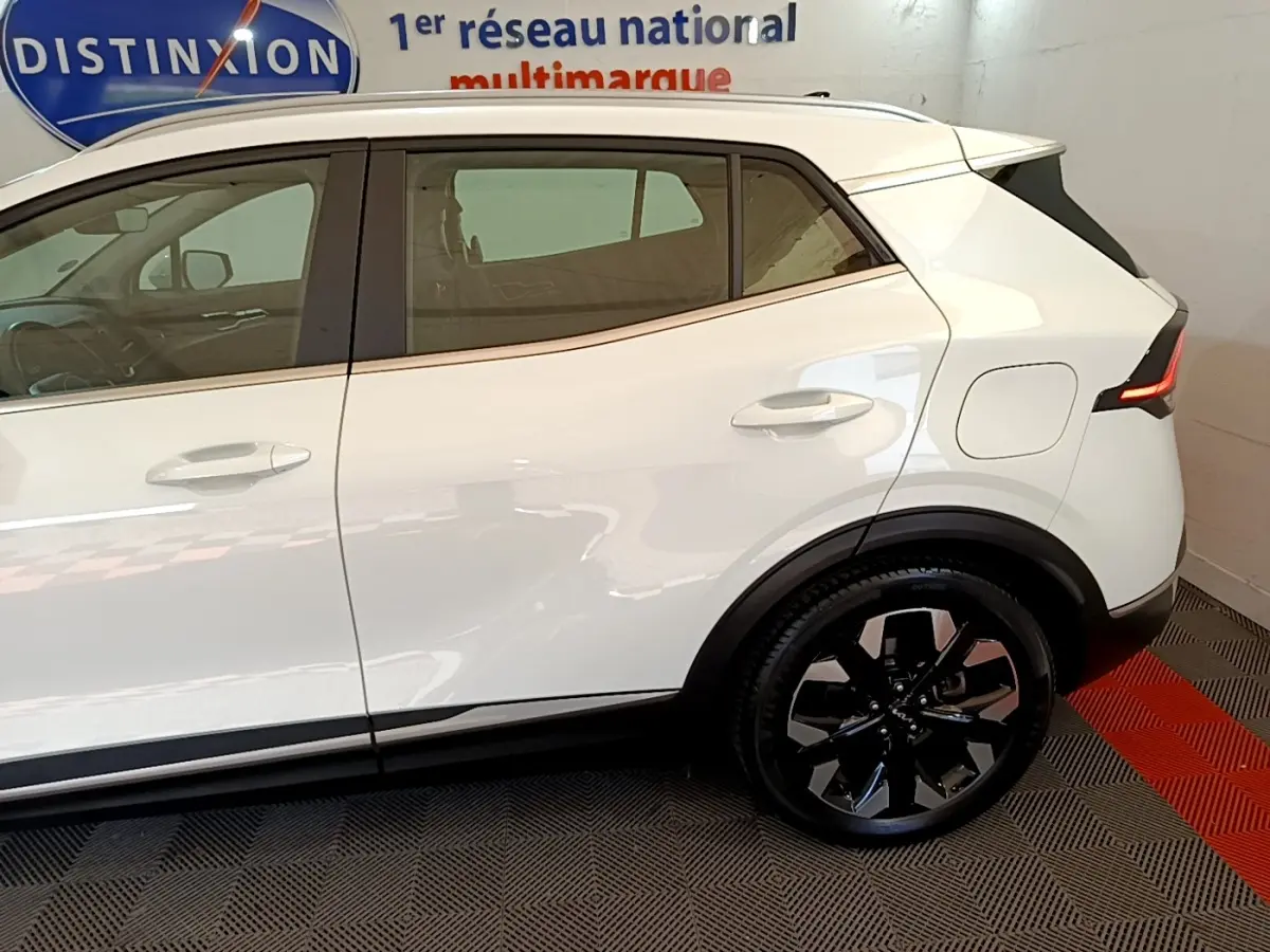 Profil droit du Kia Sportage blanc 2022 hybride rechargeable, avec jantes noires et feux arrière LED distinctifs.