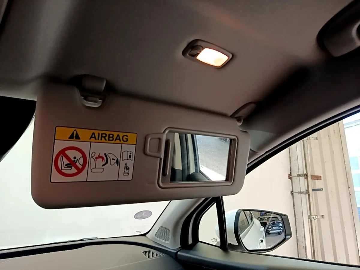 Vue intérieure du pare-soleil côté conducteur avec miroir et airbag dans un KIA Sportage blanc de 2022.