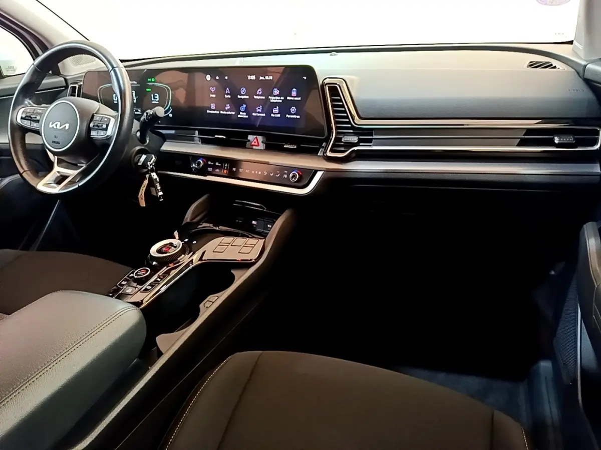 Intérieur noir du Kia Sportage 2022 vu côté conducteur, avec tableau de bord digital et console centrale moderne.