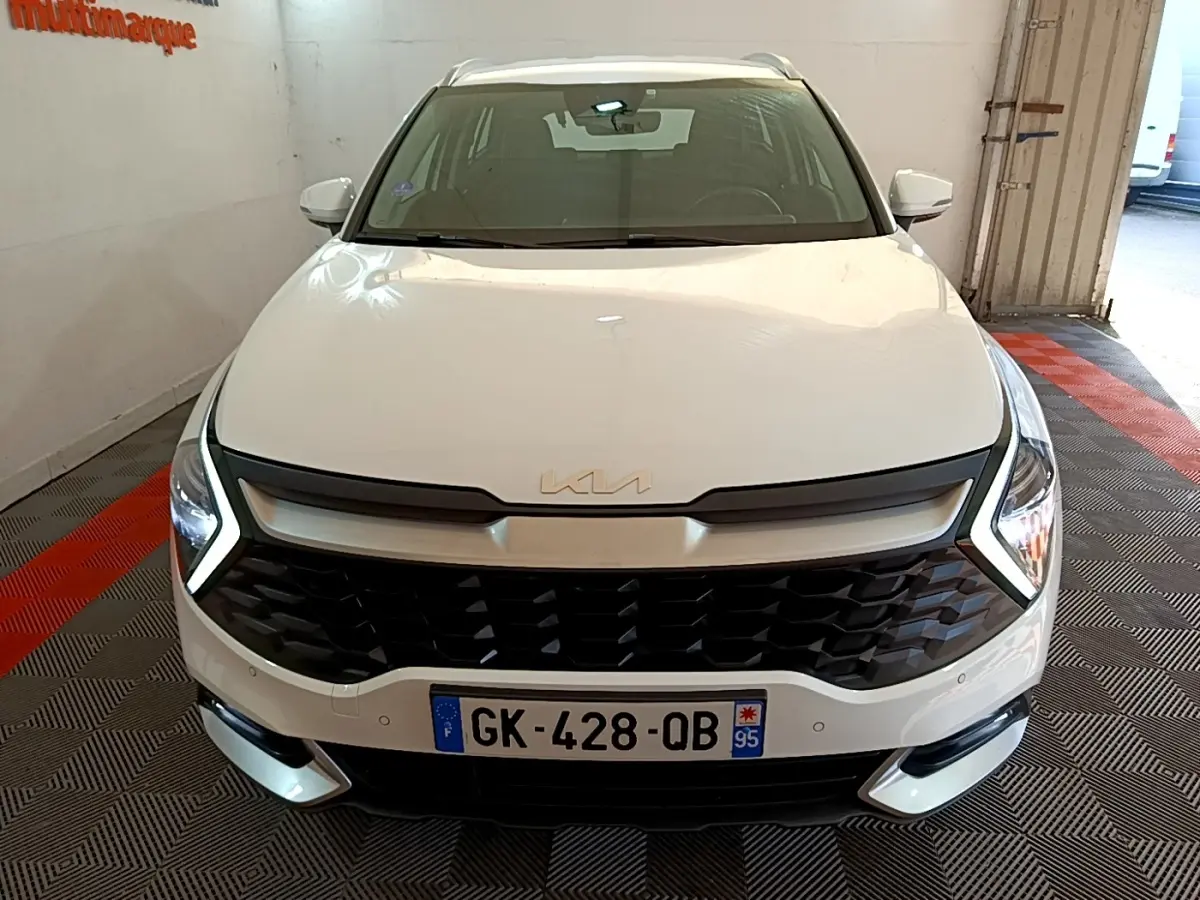Vue avant d'un KIA Sportage blanc 2022 avec calandre noire et phares LED en V distinctifs.