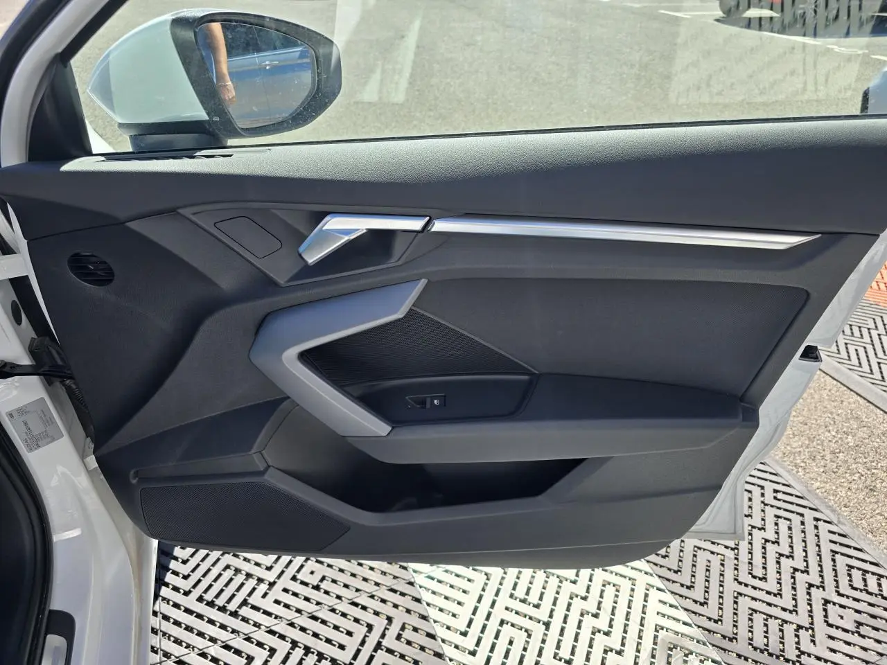 Vue intérieure côté gauche de la porte avant d’une Audi A3 Sportback blanche avec garniture noire et insert argenté.