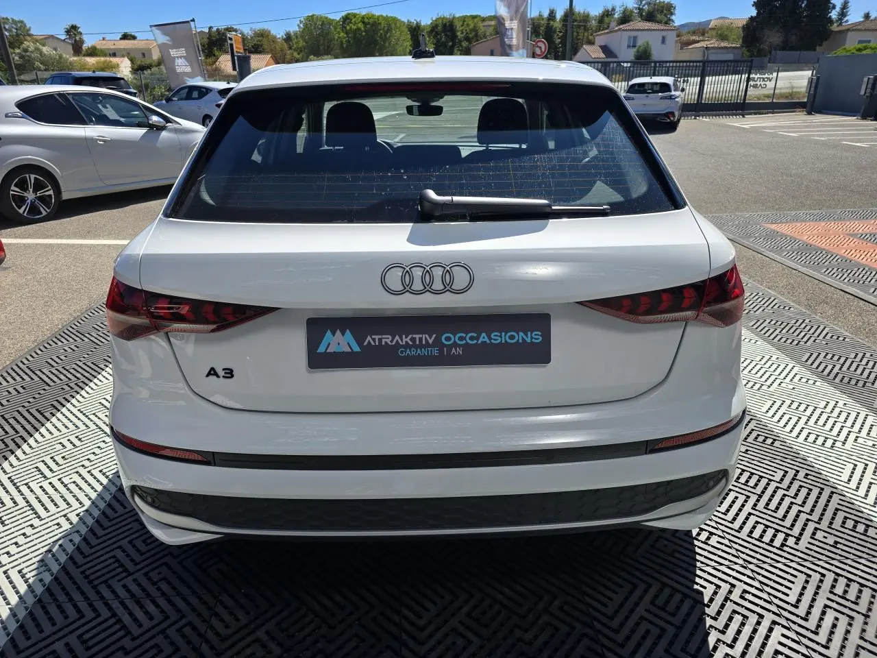 Vue arrière d'une Audi A3 Sportback 2024 en blanc Arkona avec feux arrière LED et logo Audi visible.