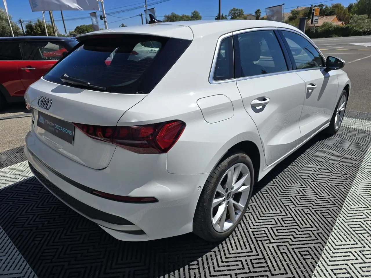 Audi A3 Sportback blanc Arkona vue 3/4 arrière droit, avec jantes alliage 5 branches et feux arrière LED distinctifs.