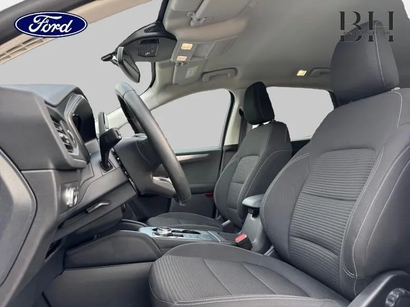 Vue intérieure côté conducteur du Ford Kuga 2021 avec sièges sport noirs et volant cuir multifonction.
