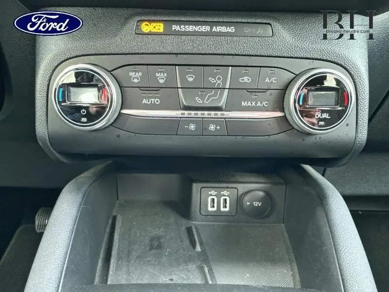 Vue rapprochée de la console centrale du Ford Kuga blanc glacier 2021, montrant les commandes de climatisation bi-zone et ports USB.