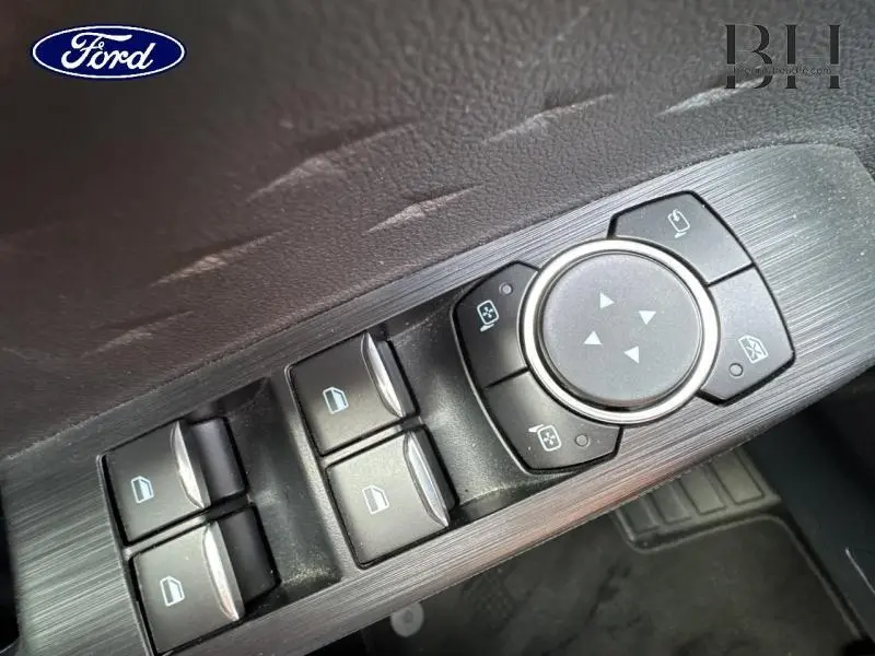 Gros plan sur les commandes de lève-vitres et réglage des rétroviseurs côté conducteur du Ford Kuga blanc Glacier 2021.