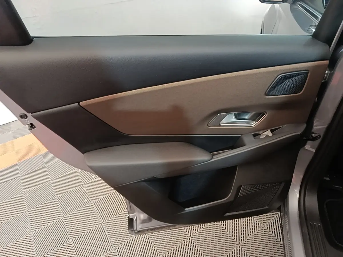 Vue intérieure de la porte arrière droite du DS7 Crossback gris foncé, avec garniture bicolore et poignée métallique.