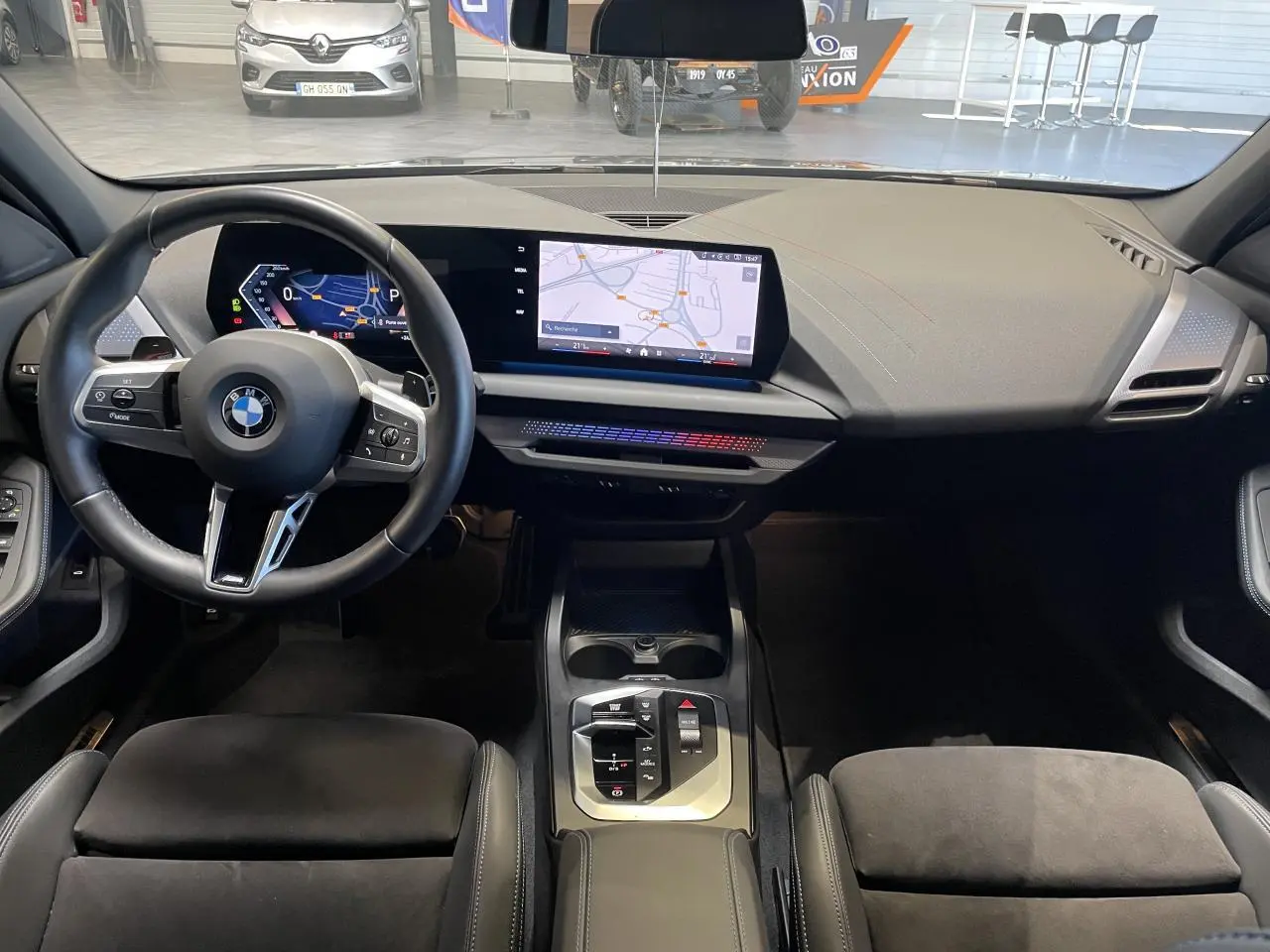 Vue intérieure avant de la BMW Série 1 120d M Sport 2025, tableau de bord moderne avec écran large et volant cuir noir.