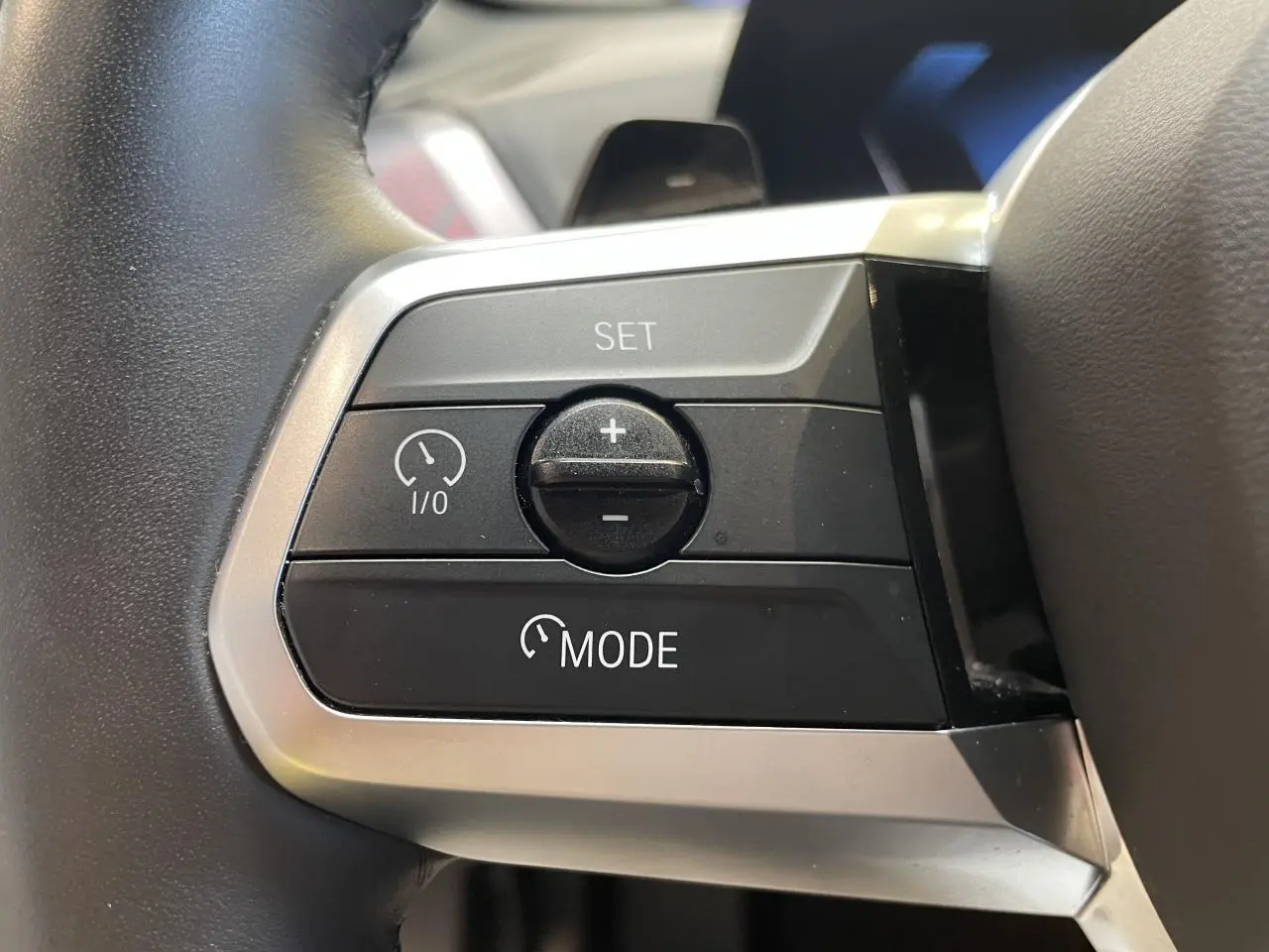 Gros plan sur les commandes de régulateur de vitesse au volant cuir noir de la BMW Série 1 120d M Sport 2025.