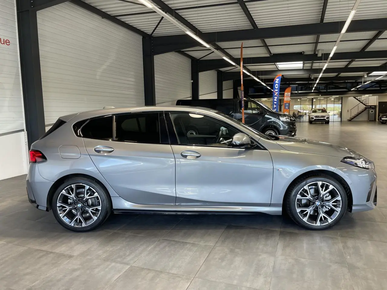 BMW Série 1 120d M Sport gris vue de profil côté gauche avec jantes 18 pouces bicolores et détails M Sport.