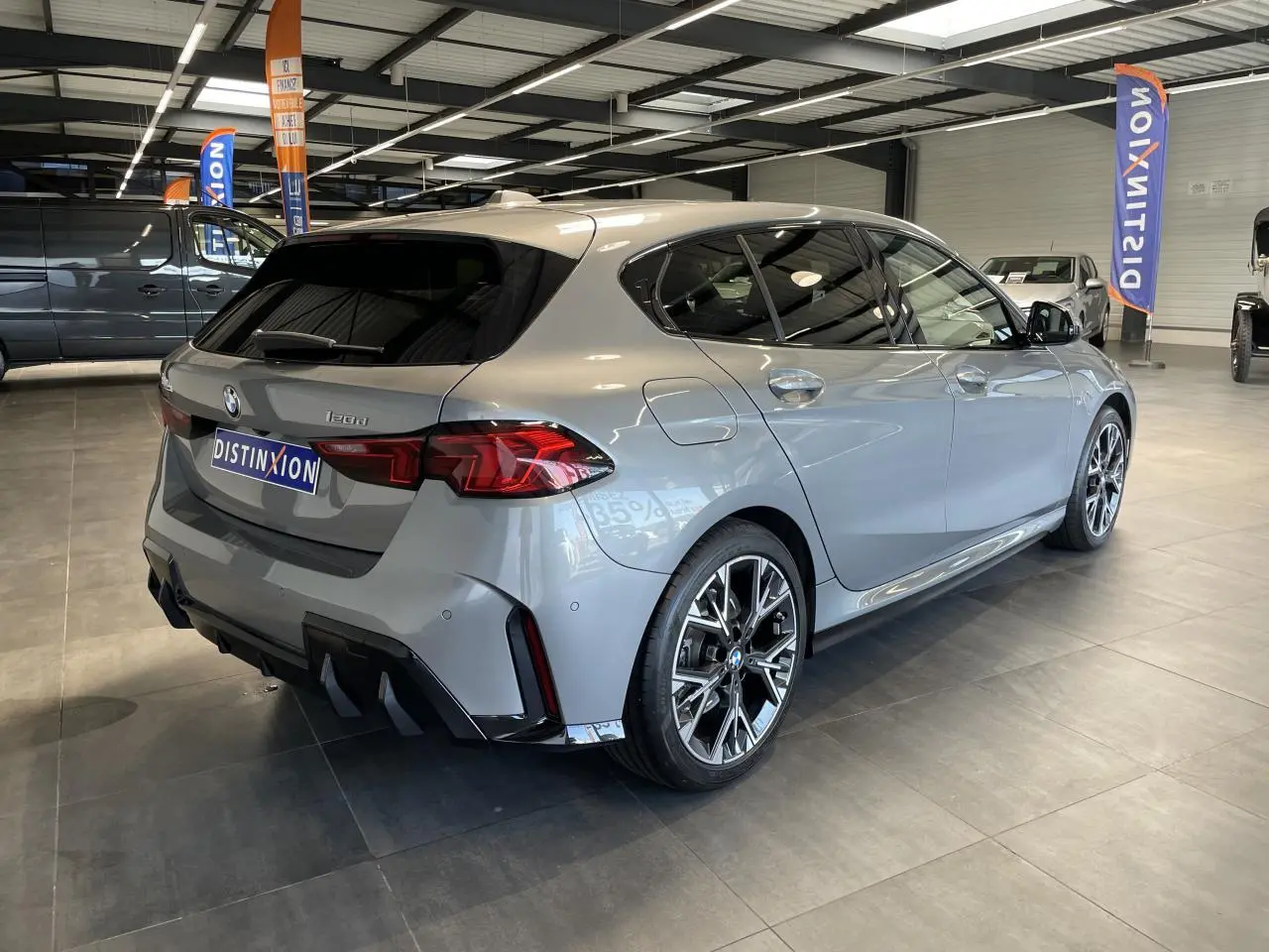 BMW Série 1 120d M Sport gris vue 3/4 arrière droit, jantes 18 pouces bicolores et diffuseur noir M Sport.