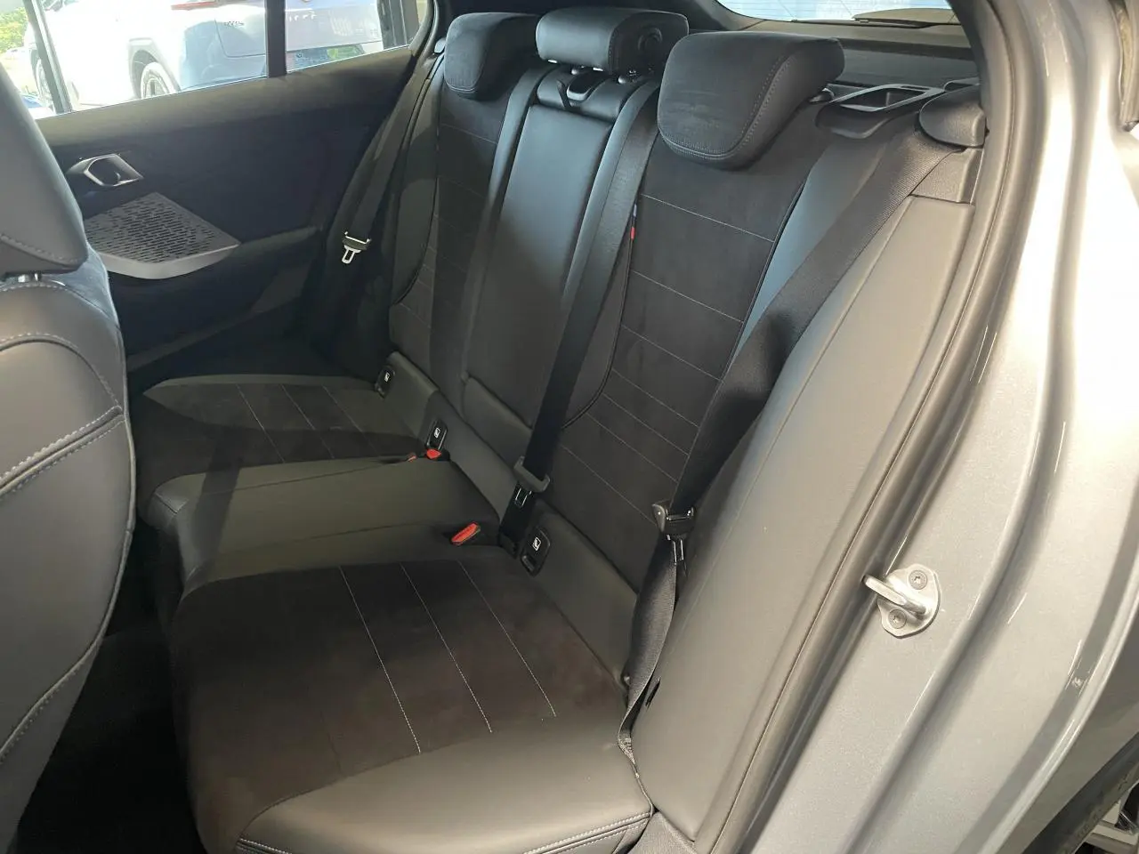 Vue intérieure côté droit des sièges arrière noirs en Alcantara et cuir d'une BMW Série 1 120d M Sport gris.