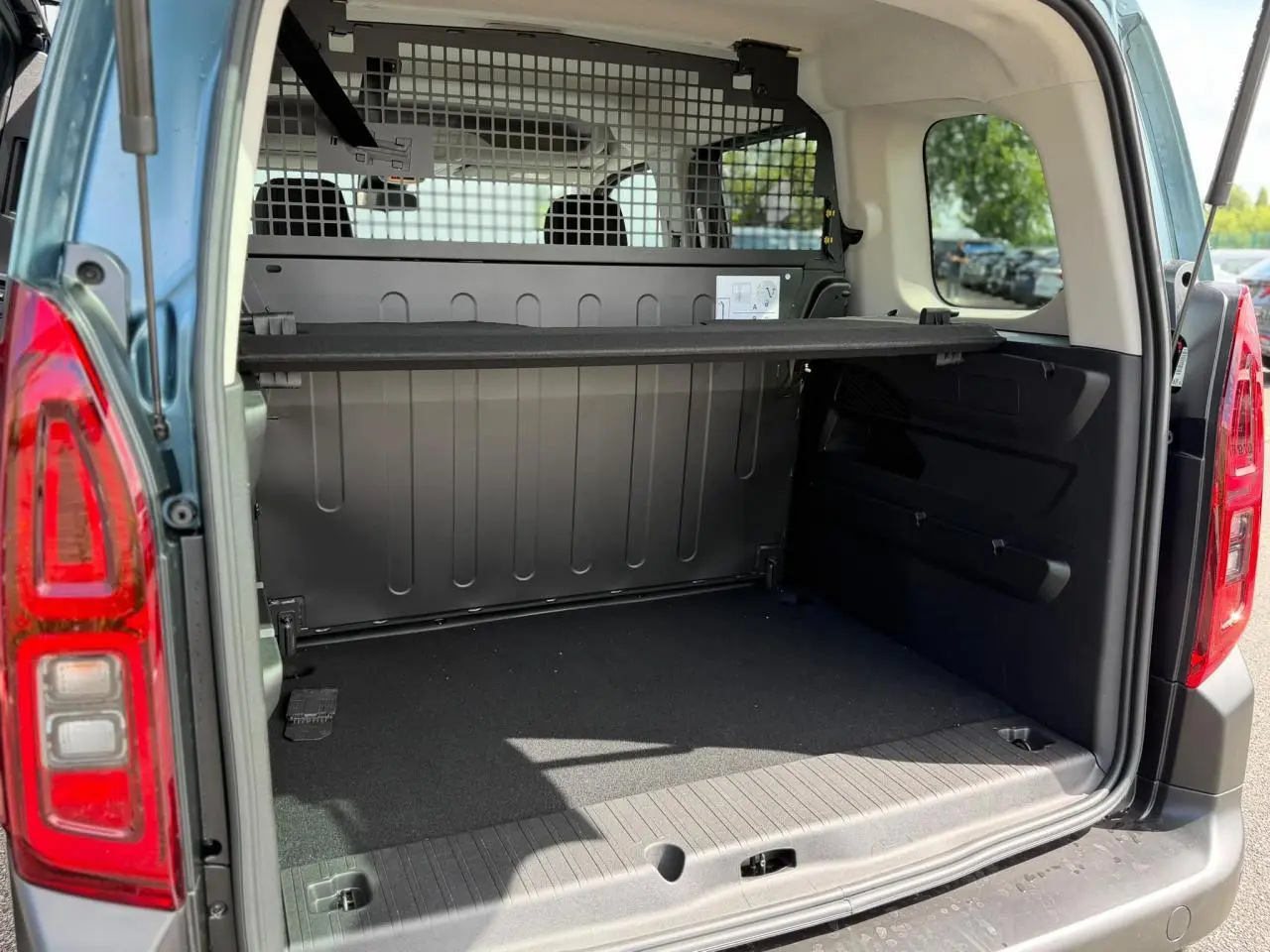 Coffre arrière ouvert du Citroën Berlingo Multispace bleu Kiama, avec lunette arrière ouvrante et séparation grillagée.
