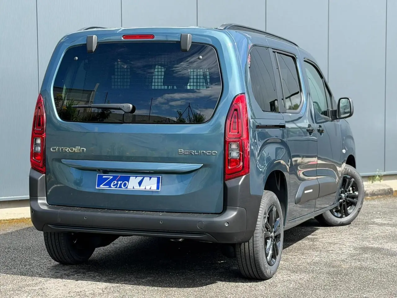 Vue 3/4 arrière droite d'un Citroën Berlingo Bleu Kiama avec lunette arrière ouvrante et jantes alliage noires.