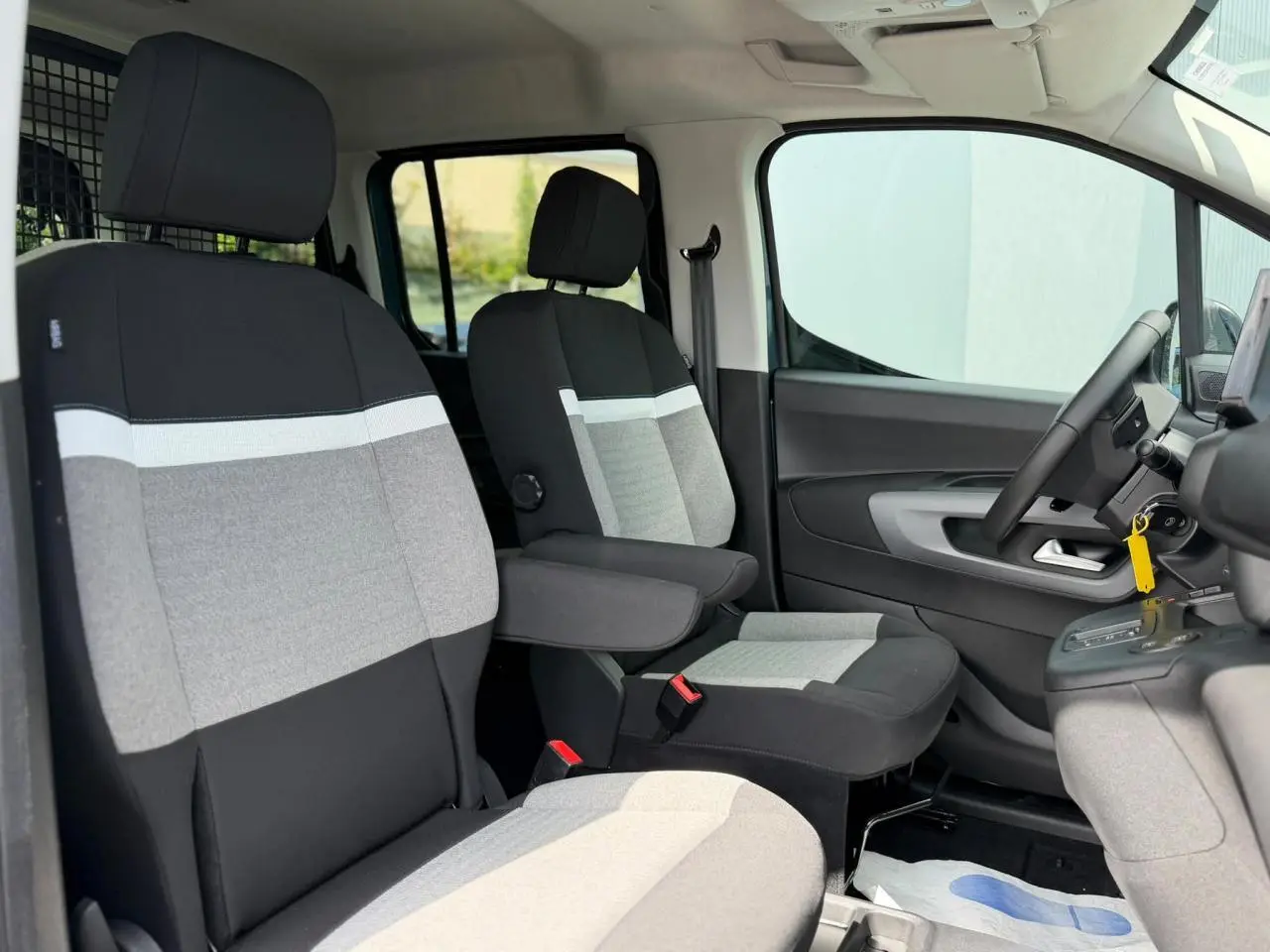 Vue intérieure côté conducteur du Citroën Berlingo Multispace 2026, sièges tissu gris et noir avec accoudoir.