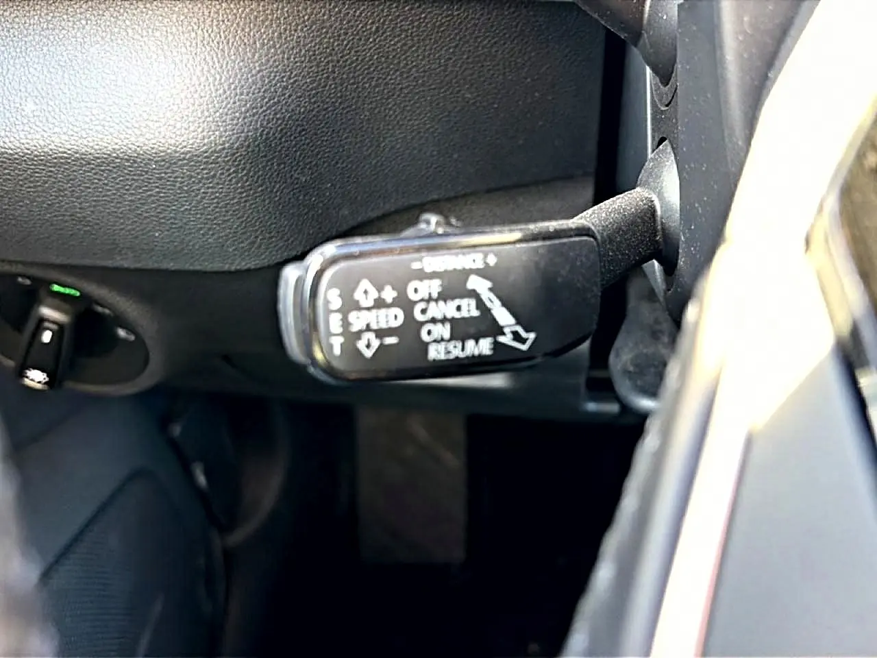 Gros plan sur la commande de régulateur de vitesse à gauche du volant dans l’habitacle gris du Skoda Karoq 2025.