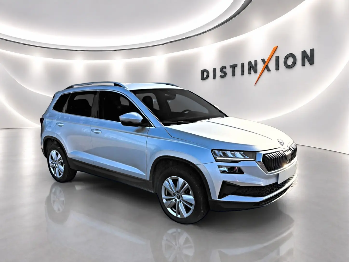 Vue 3/4 avant droite d'un Skoda Karoq gris métallisé dans un showroom lumineux avec jantes alu.