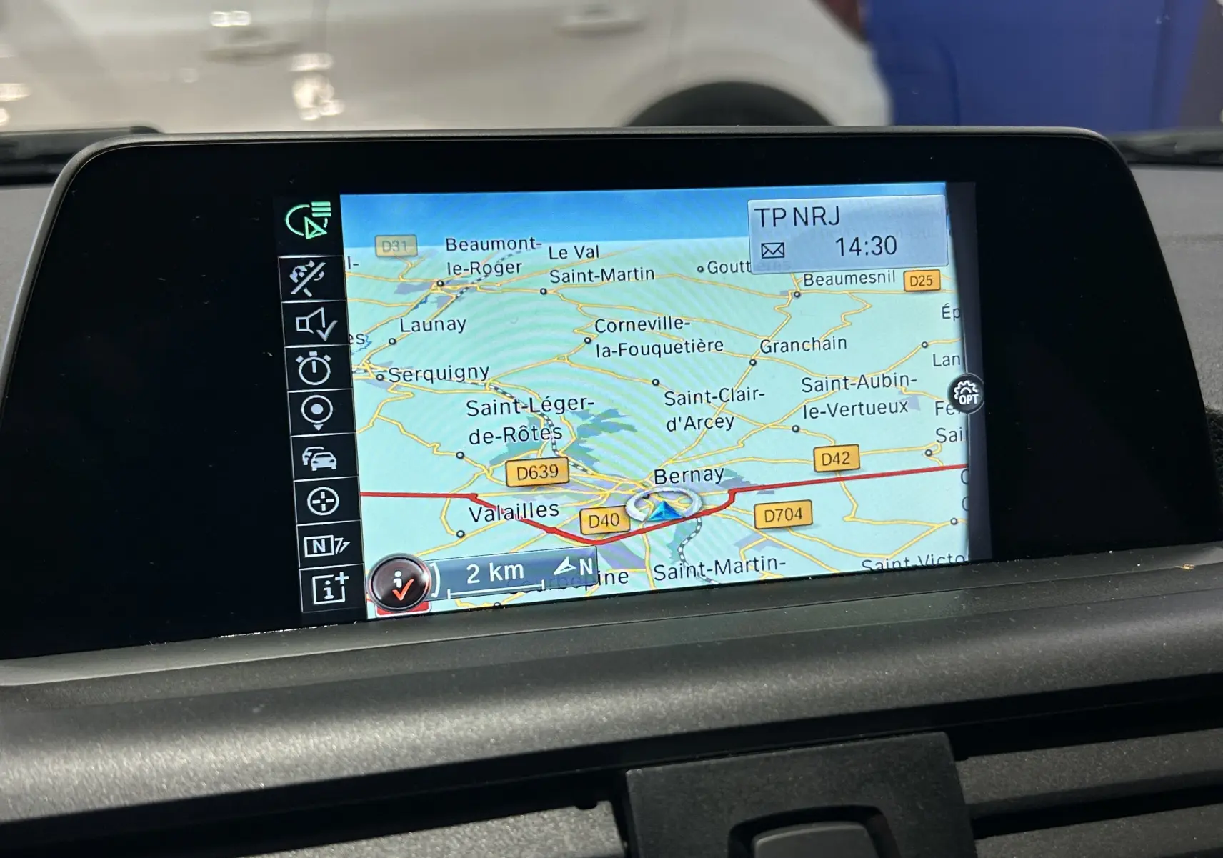 Écran de navigation GPS affichant une carte routière, vu de face à l'intérieur d'une BMW Série 1 blanche.
