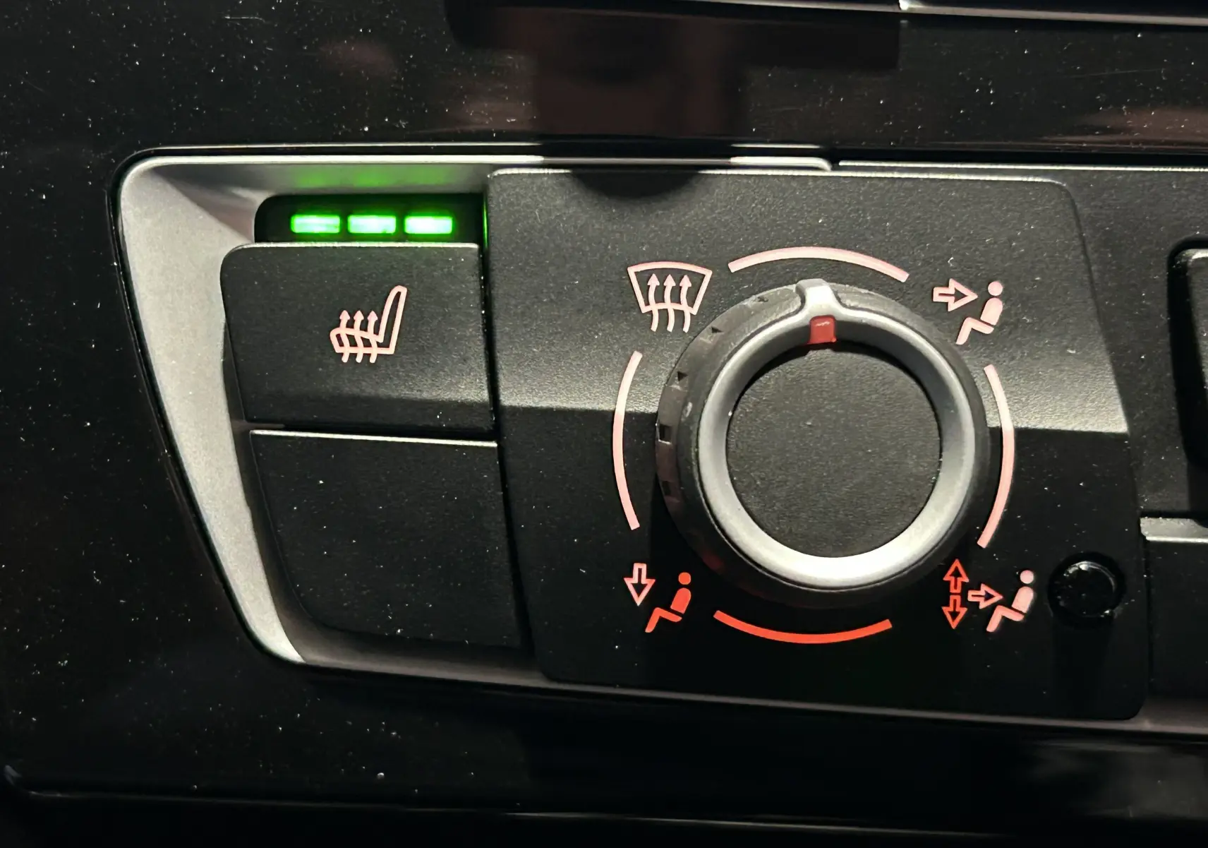 Gros plan sur le bouton de réglage de ventilation et siège chauffant activé avec trois voyants verts dans une BMW Série 1 blanche.