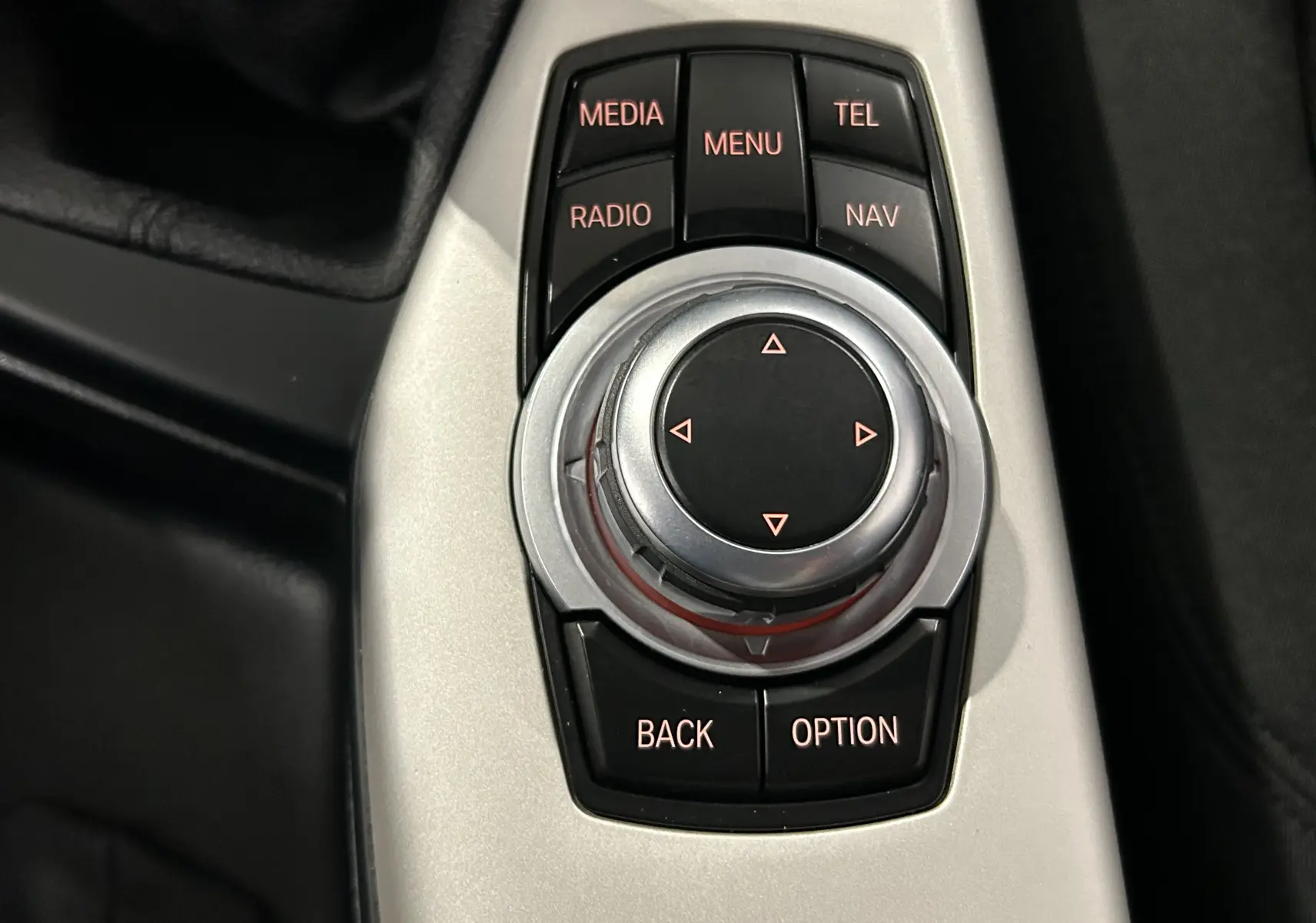 Gros plan sur la molette de commande centrale noire et argentée du BMW Série 1 116d blanc, avec boutons fonctionnels visibles.