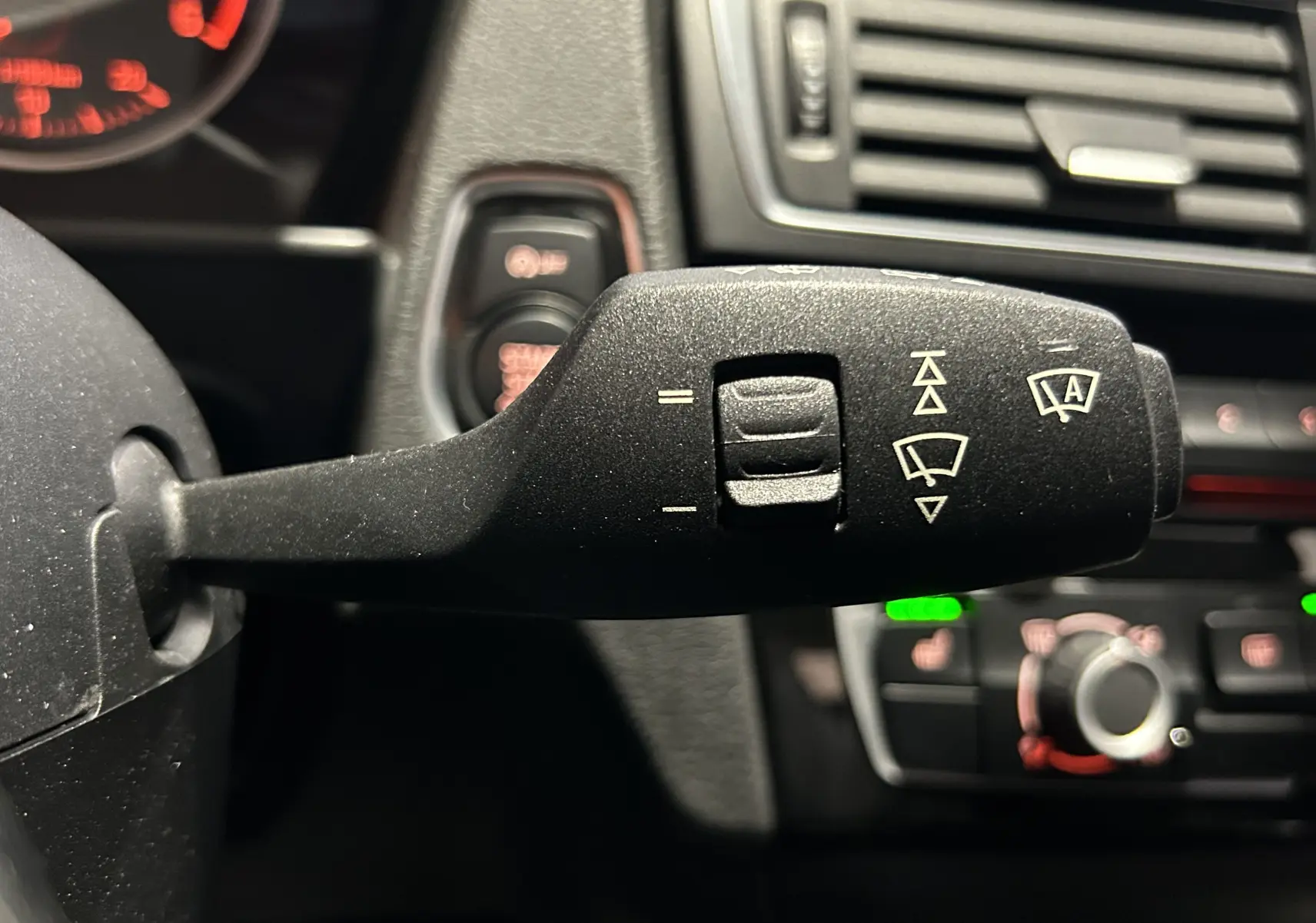 Gros plan sur la commande d’essuie-glace à gauche du volant dans l’habitacle d’une BMW Série 1 blanche de 2015.
