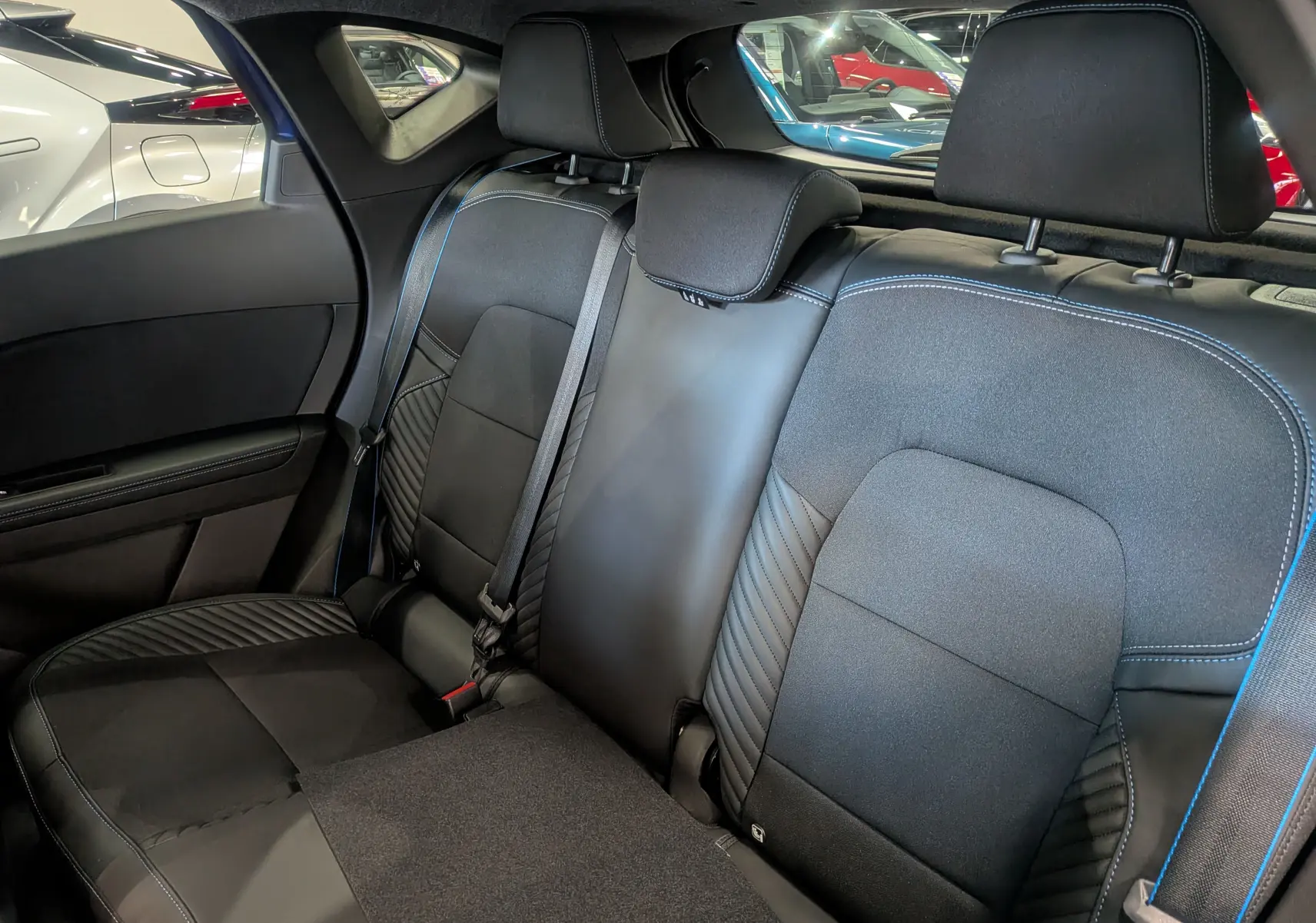 Vue intérieure des sièges arrière en cuir noir avec surpiqûres bleues du Renault Captur E-TECH Full Hybrid 2025.