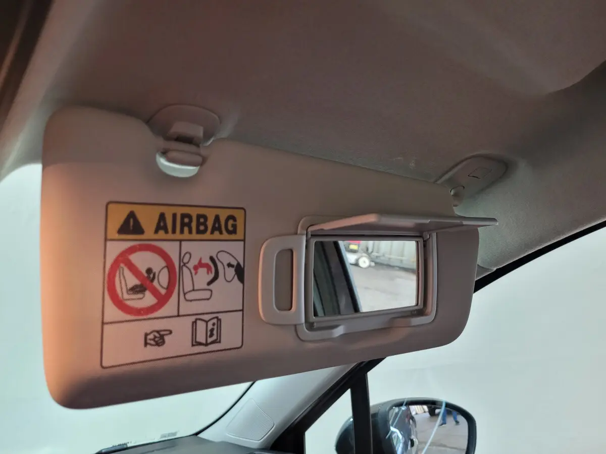 Miroir de courtoisie ouvert sur pare-soleil côté conducteur dans Renault Clio gris foncé, vue intérieure avant gauche.