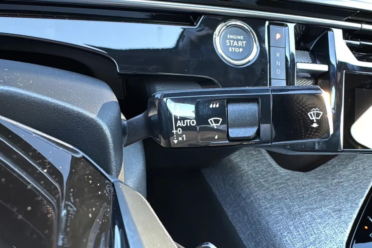 Gros plan sur la commande d’essuie-glace et le bouton start/stop dans l’habitacle du Peugeot 3008 Hybrid blanc toit noir.