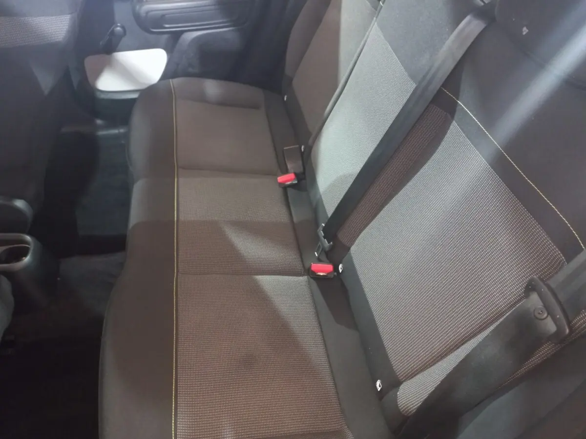 Vue intérieure de la banquette arrière grise et noire de la Citroën C3 2024 avec ceintures et boucle rouge visibles.