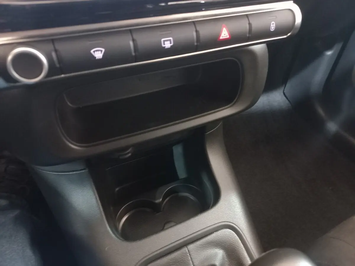 Gros plan sur la console centrale noire d'une Citroën C3 2024, montrant les boutons de commande et porte-gobelets.