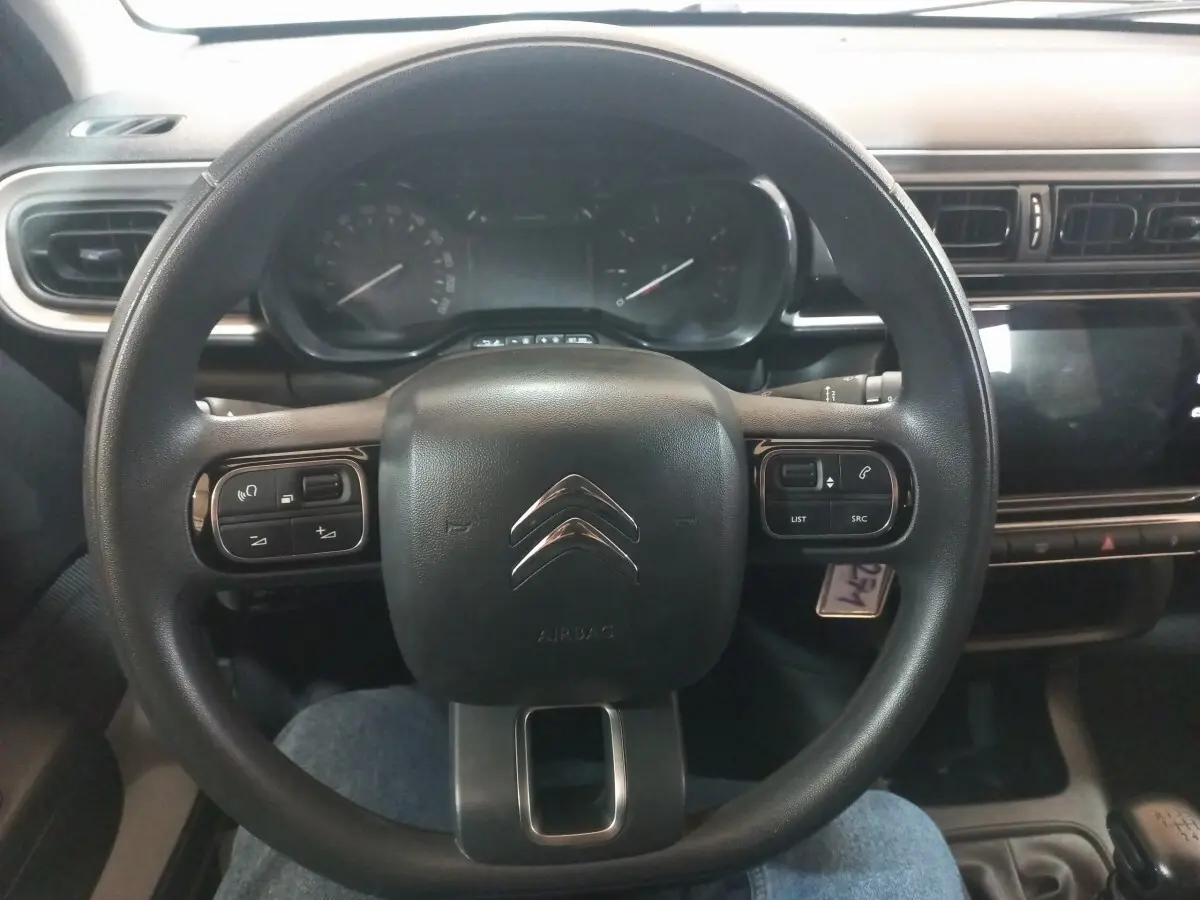 Vue frontale du volant noir de la Citroën C3 2024 avec commandes intégrées et tableau de bord digital.