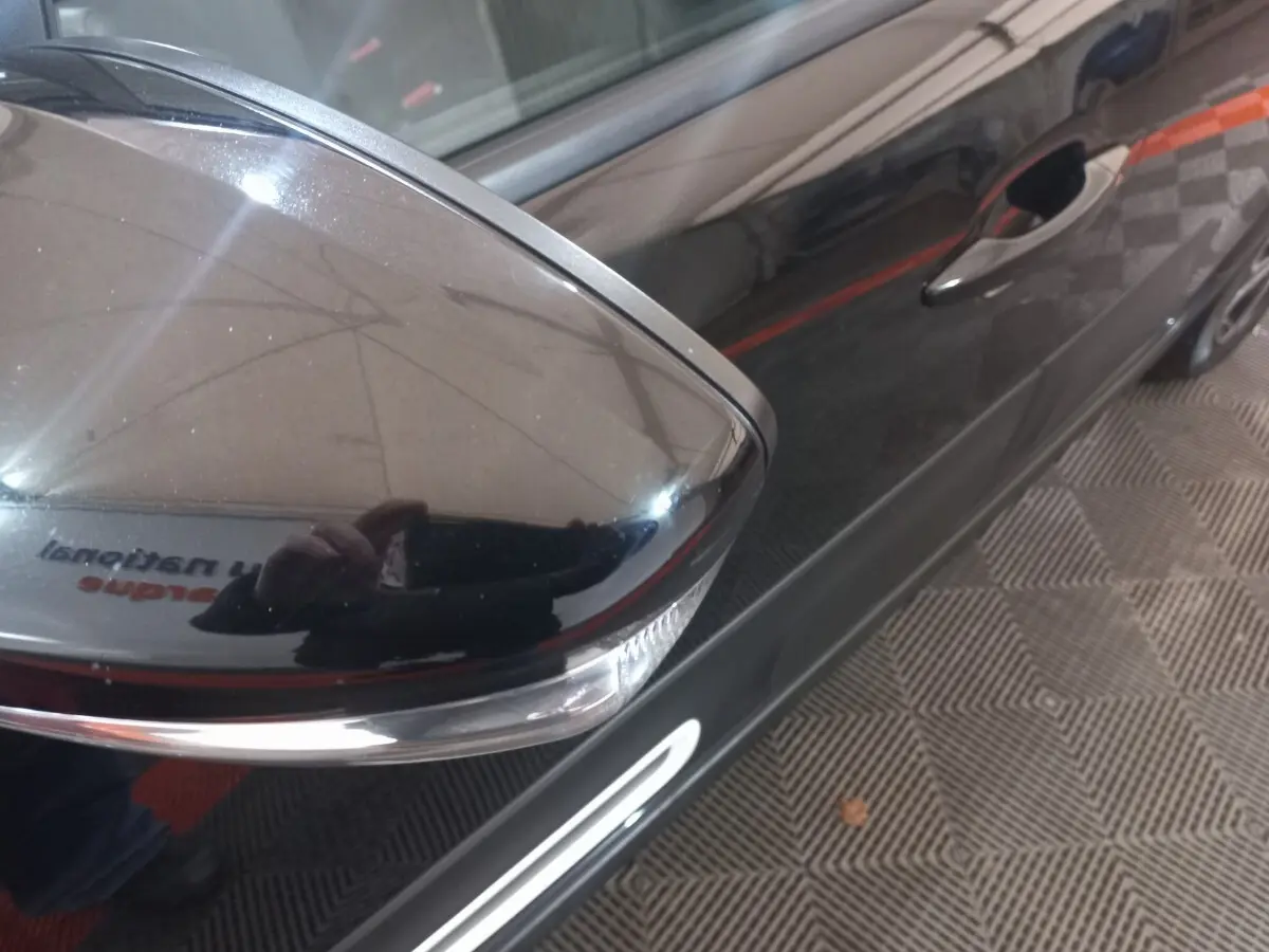 Gros plan sur le rétroviseur droit noir brillant de la Citroën C3 2024, avec poignée de porte et partie latérale visibles.