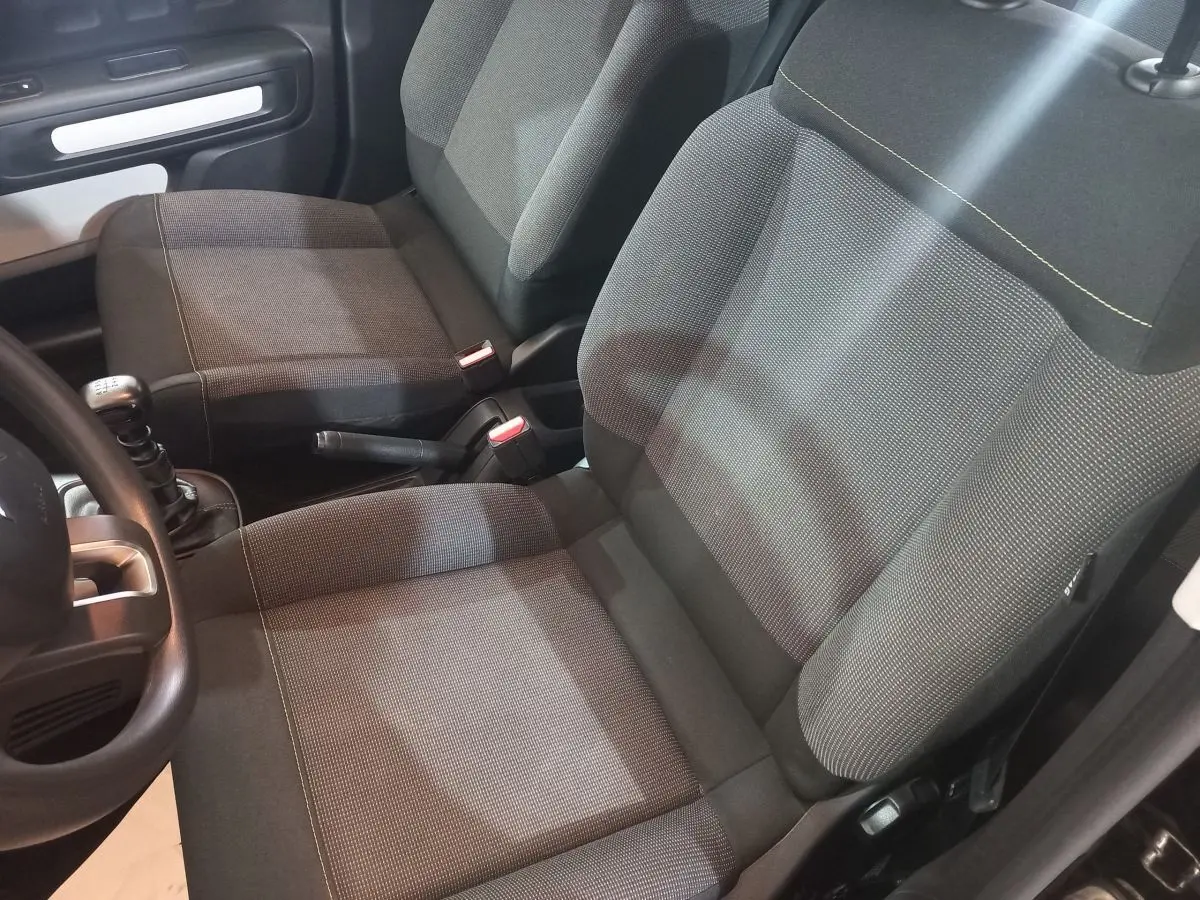 Vue intérieure rapprochée des sièges avant gris foncé de la Citroën C3 BlueHDi 100 BVM PLUS 2024 avec levier de vitesses manuel.