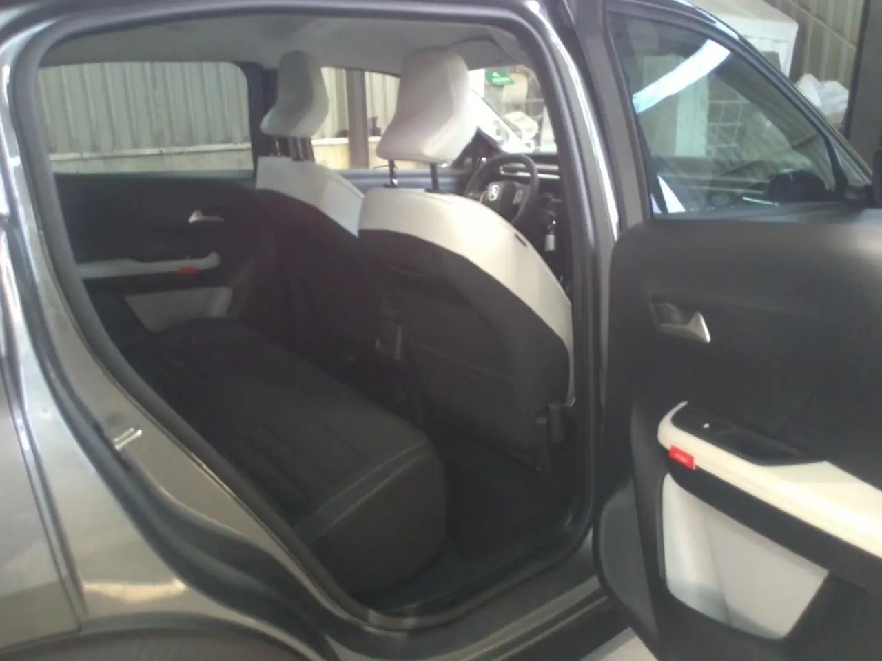 Vue intérieure côté gauche montrant la banquette arrière noire et les sièges avant bicolores du Citroën C3 Aircross gris Mercury.