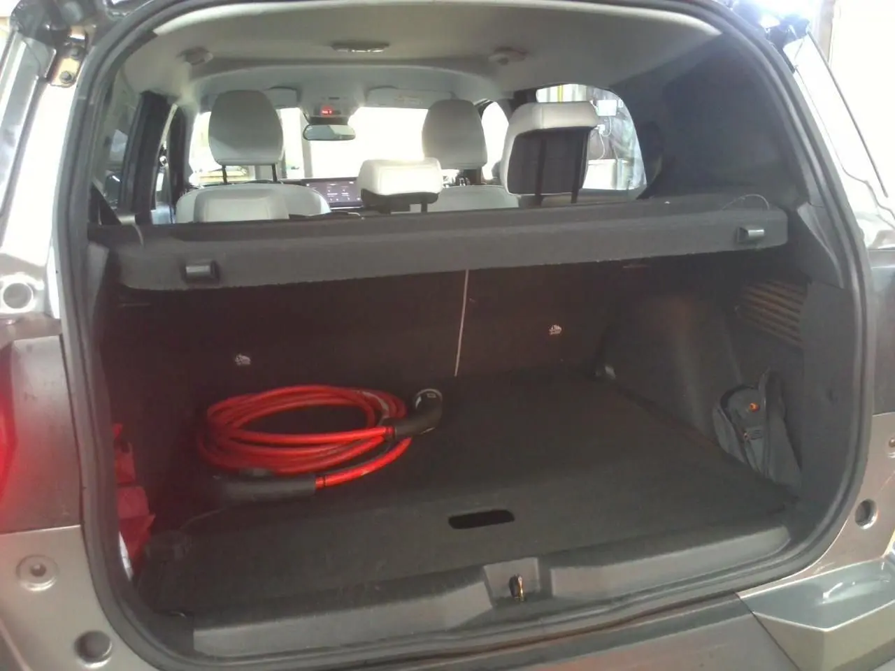 Coffre ouvert d’un Citroën C3 Aircross électrique gris Mercury, avec câble de recharge rouge visible à l’intérieur.