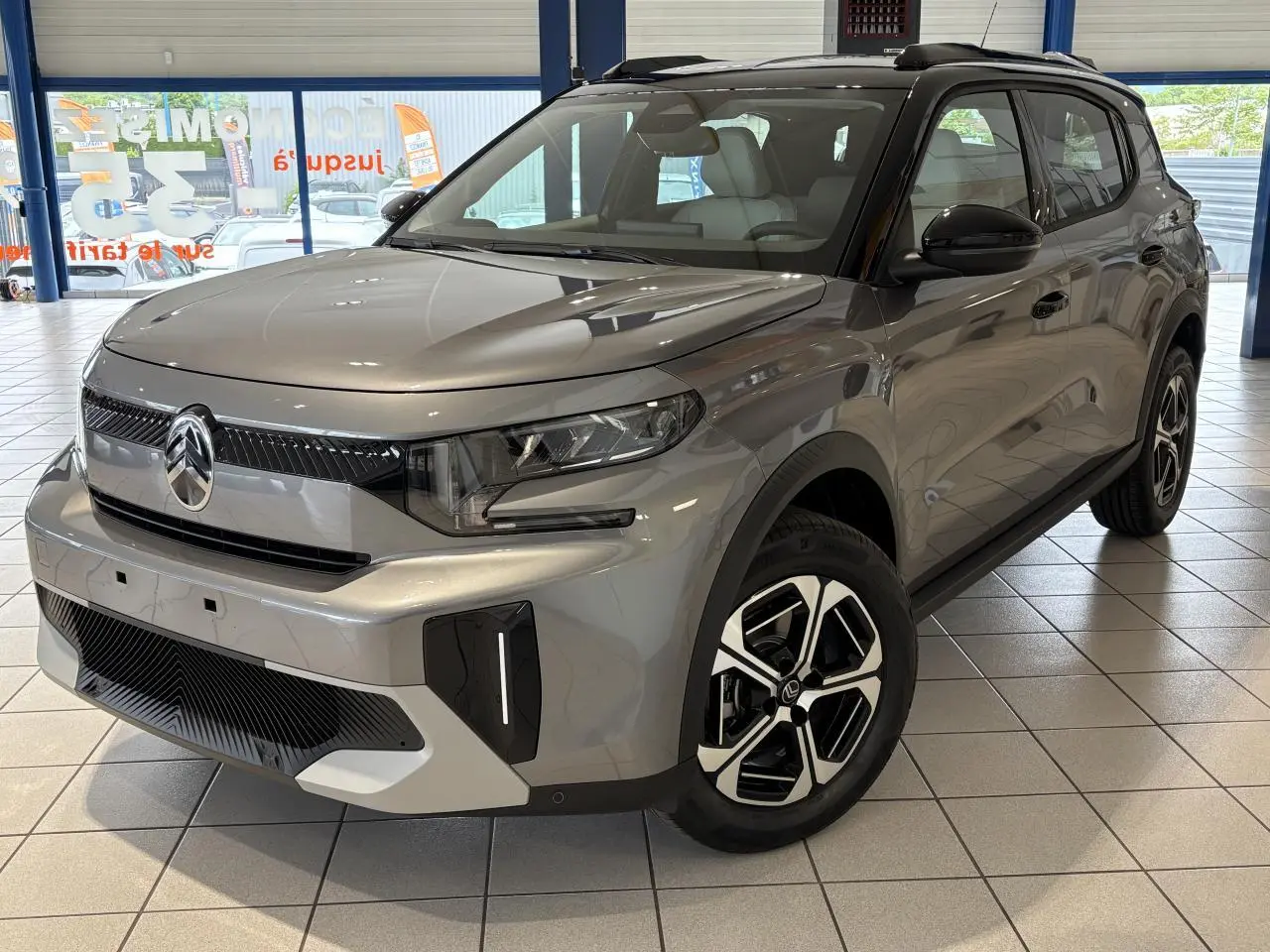 Vue 3/4 avant d'un Citroën C3 Aircross 2026 gris métallisé avec toit noir et jantes diamantées noires et argent.