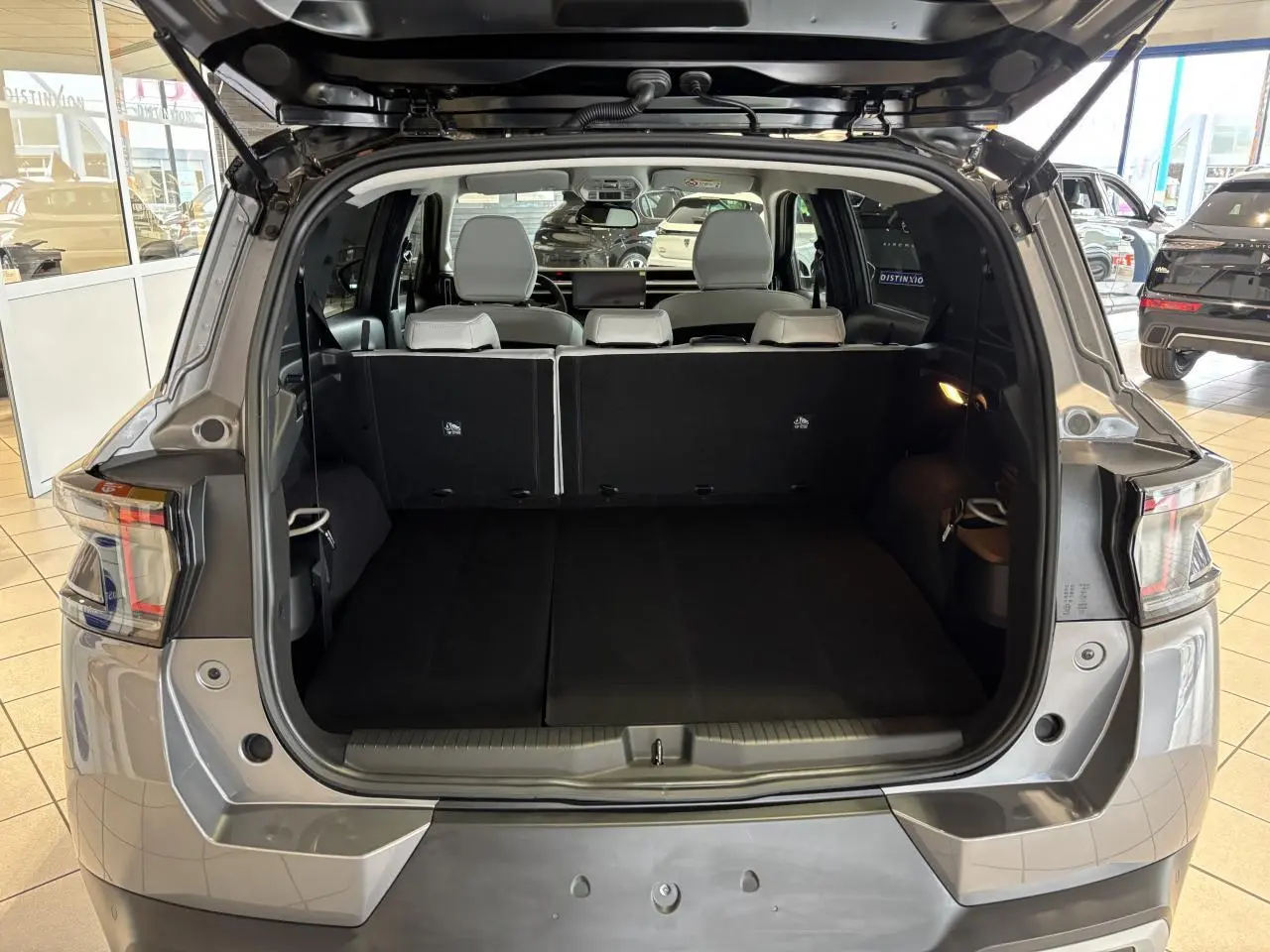 Coffre ouvert vue arrière du Citroën C3 Aircross gris avec banquette arrière noire et sièges blancs visibles.