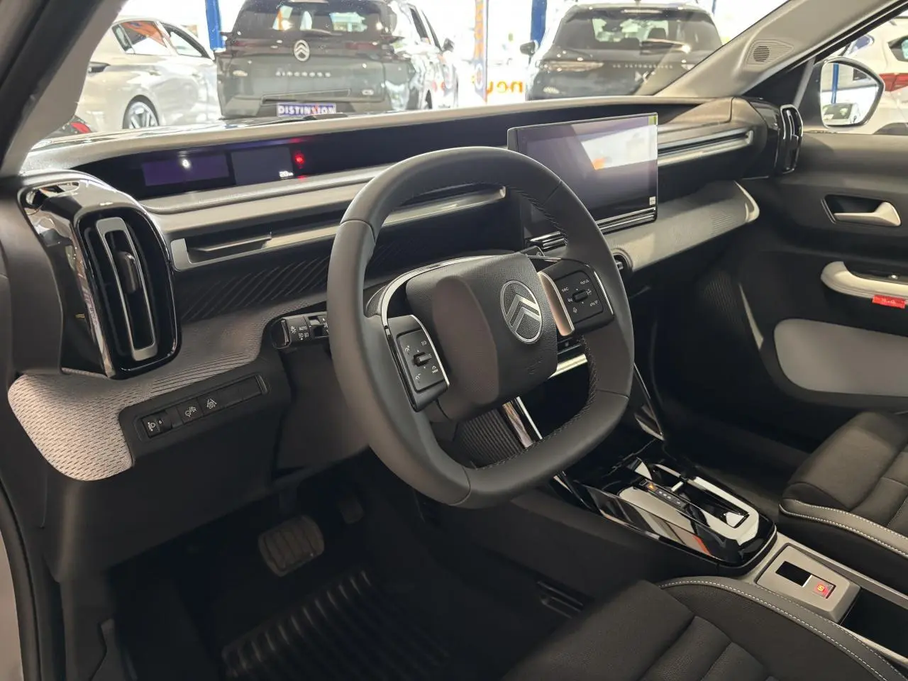 Vue intérieure côté conducteur du Citroën C3 Aircross 2026, volant carré et tableau de bord moderne noir et gris.
