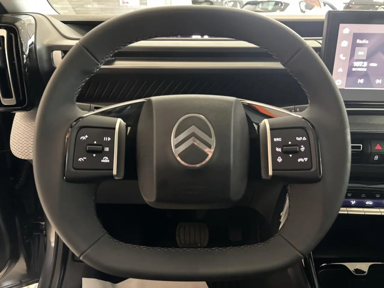 Vue rapprochée du volant multifonctions noir du Citroën C3 Aircross 2026 avec commandes tactiles et logo central chromé.