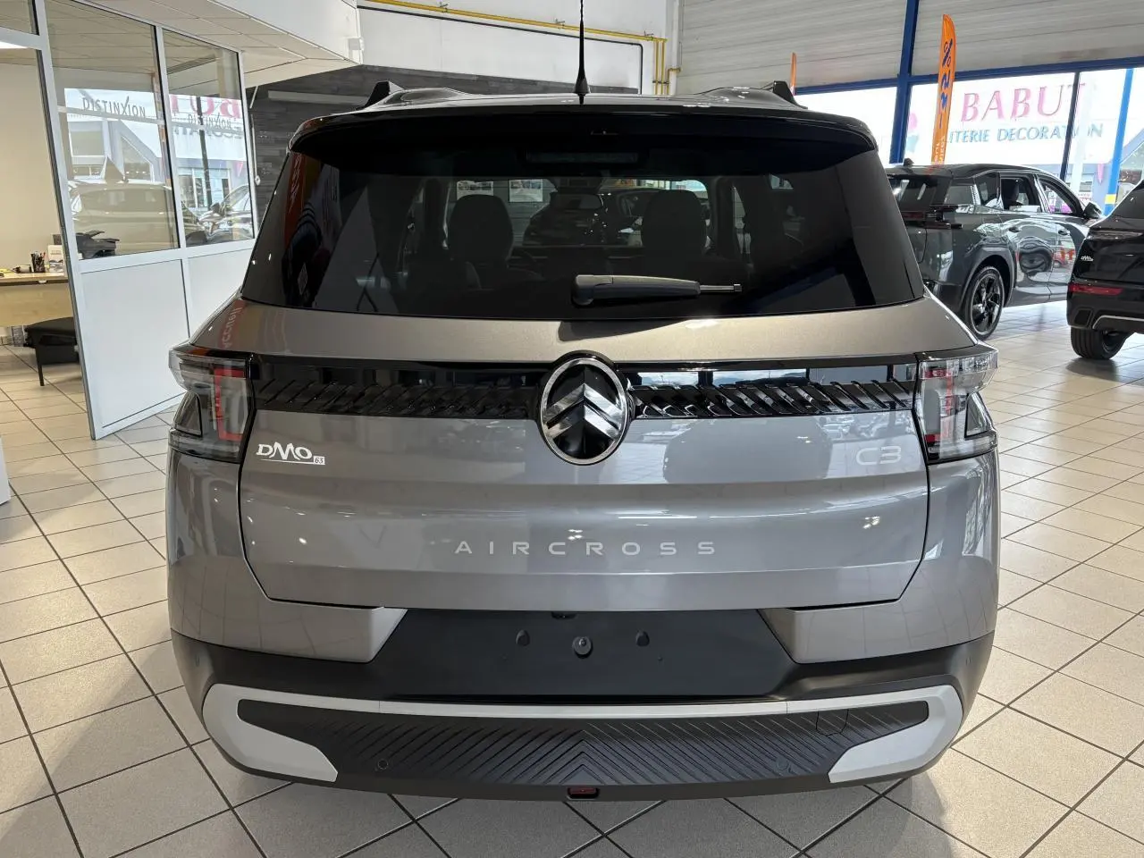 Vue arrière d'un Citroën C3 Aircross gris métallisé avec toit noir, feux arrière LED et logo central noir brillant.