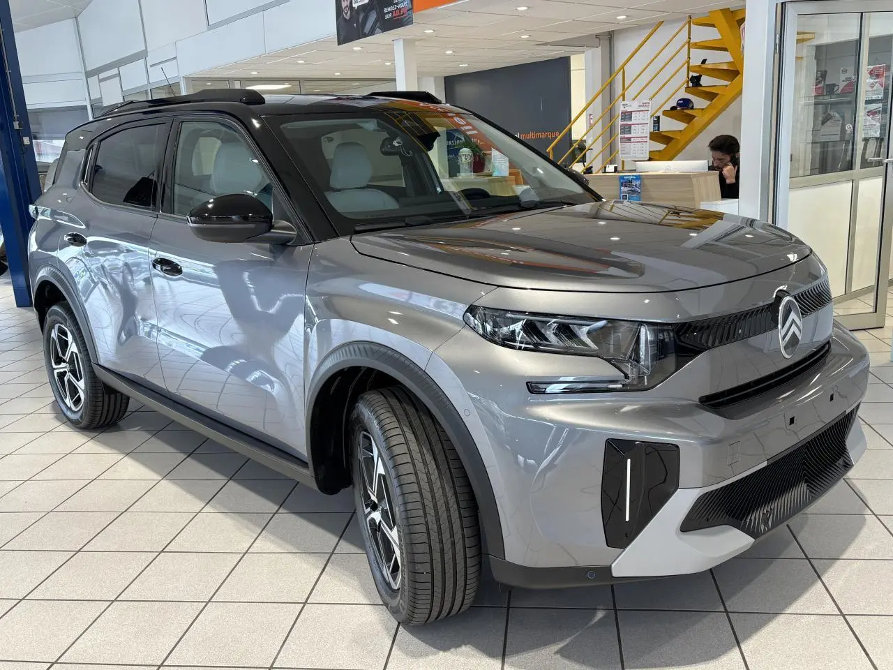 Vue 3/4 avant droite du Citroën C3 Aircross 2026 gris métallisé avec toit noir et jantes alliage diamantées.