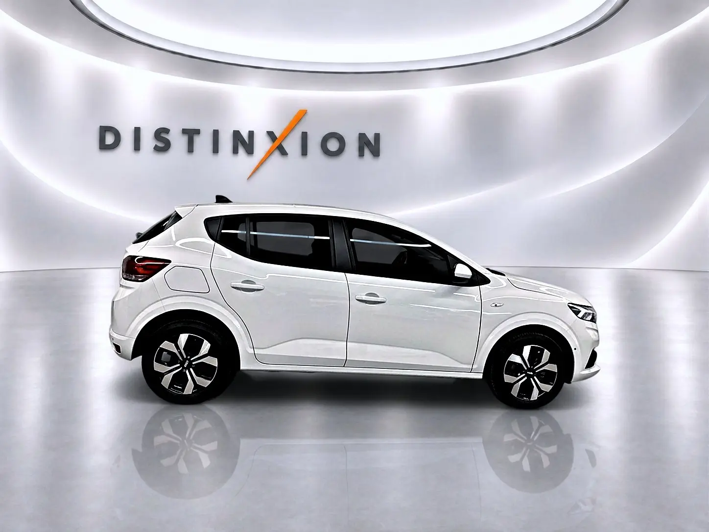 Profil droit d'une Dacia Sandero blanche 2025 dans un studio lumineux avec jantes alliage et vitres teintées.