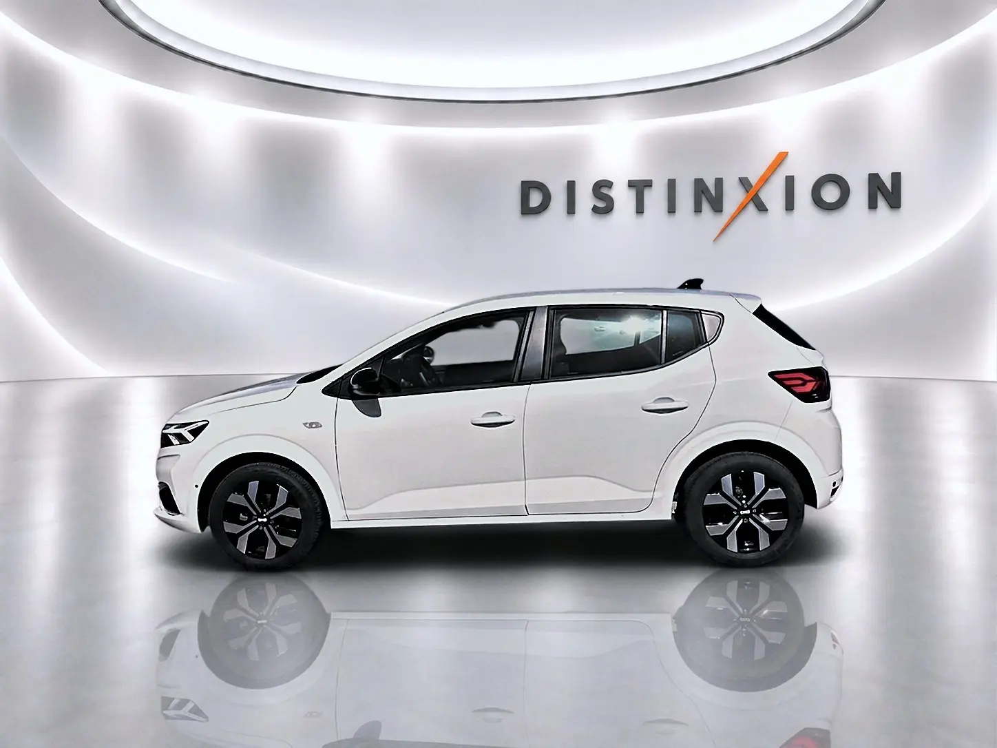 Profil droit d'une Dacia Sandero blanche 2025 dans un studio lumineux avec jantes alliage noires et logo Distinxion en arrière-plan.