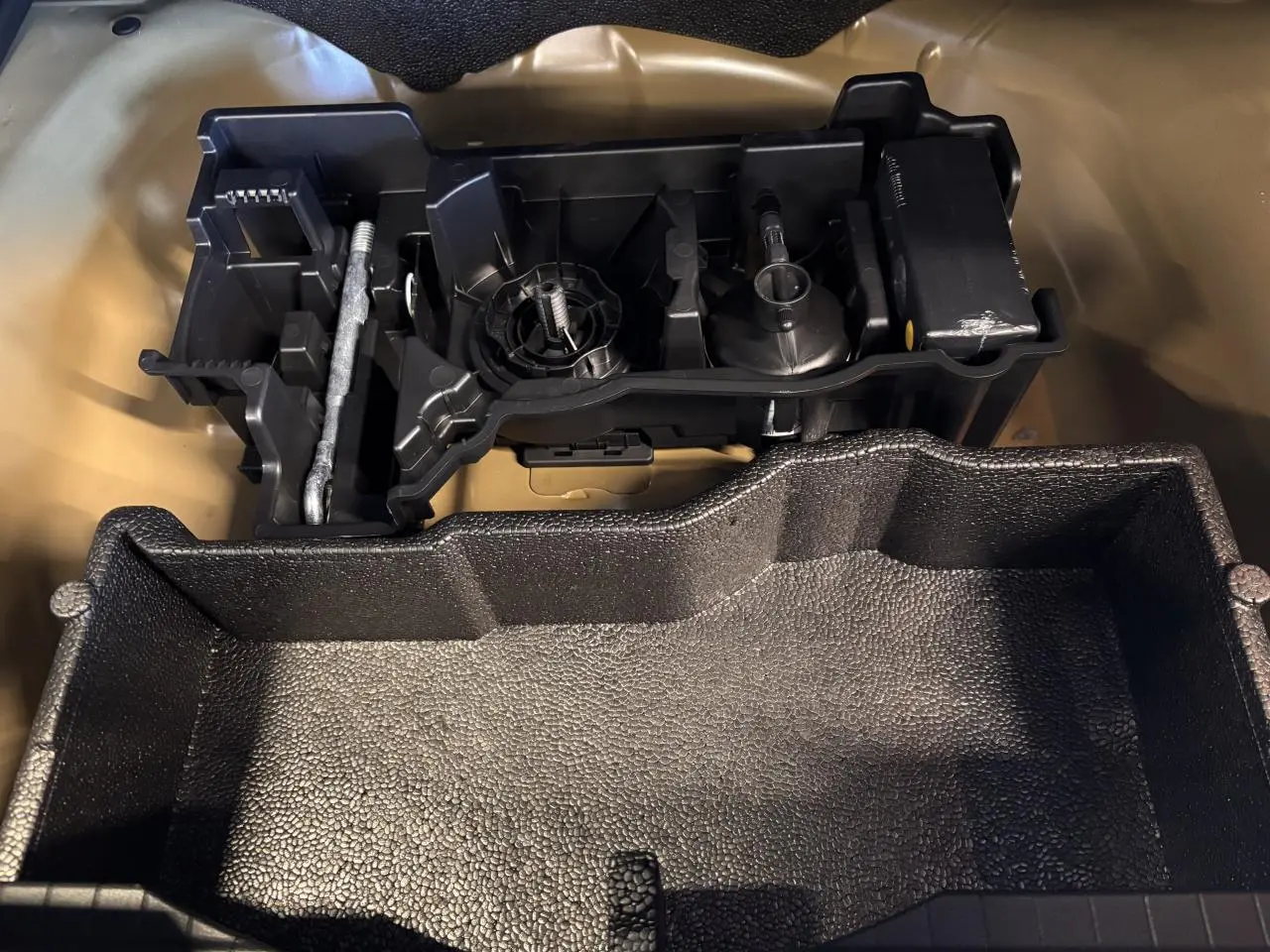 Kit de dépannage pneumatique noir dans le coffre du Peugeot 2008 gris hybride 2025, vue en plongée rapprochée.