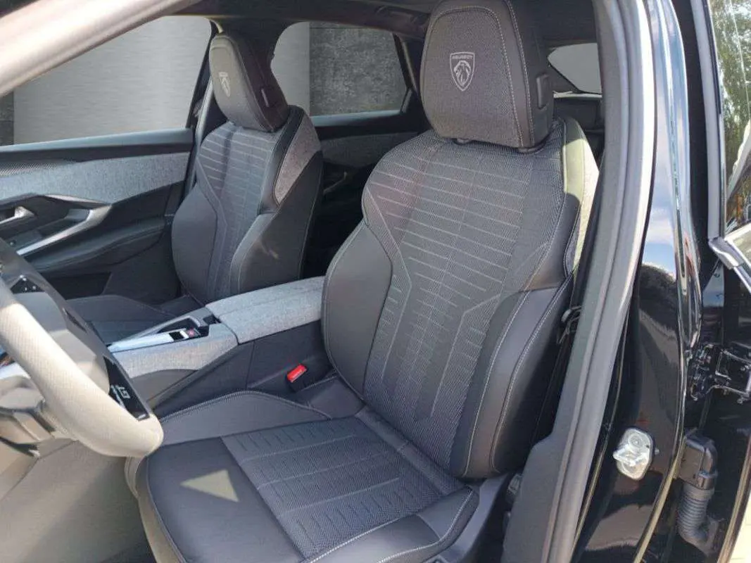 Vue intérieure côté conducteur du Peugeot 3008 New Hybrid 145 GT 360 noir perla nera, sièges tissu et cuir avec logo Peugeot brodé.