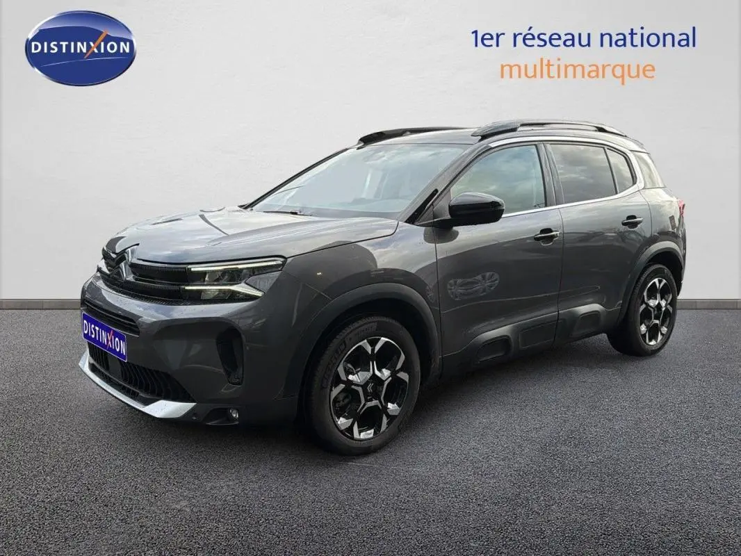 Vue 3/4 avant droite du Citroën C5 Aircross platine 2025 avec barres de toit et jantes aluminium distinctives.