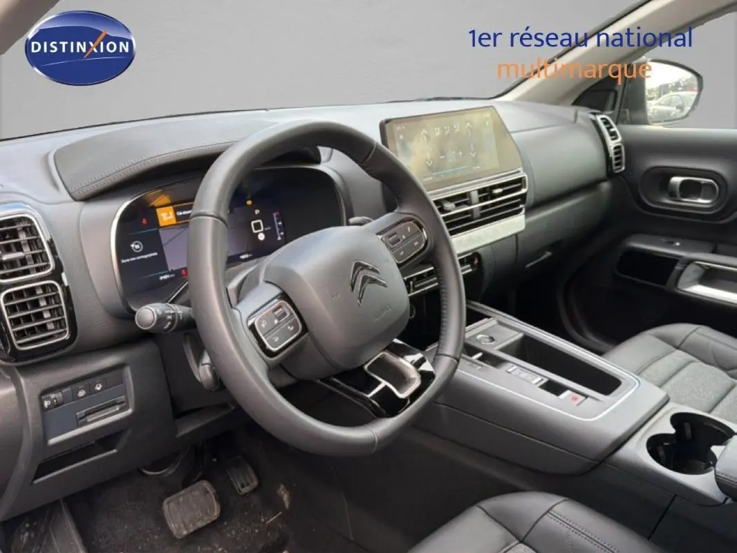 Vue intérieure côté conducteur du Citroën C5 Aircross 2025, montrant le volant cuir multifonctions et l'écran tactile central.
