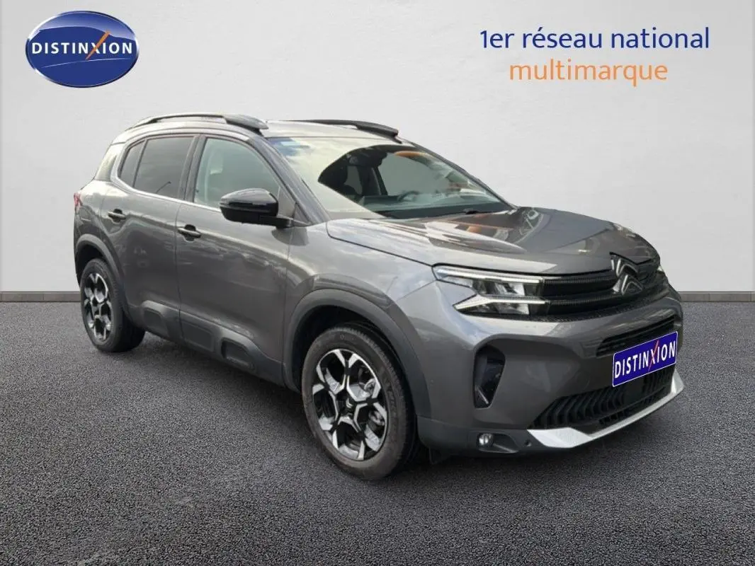 Vue 3/4 avant droite du Citroën C5 Aircross platine 2025 avec barres de toit et jantes aluminium distinctives.